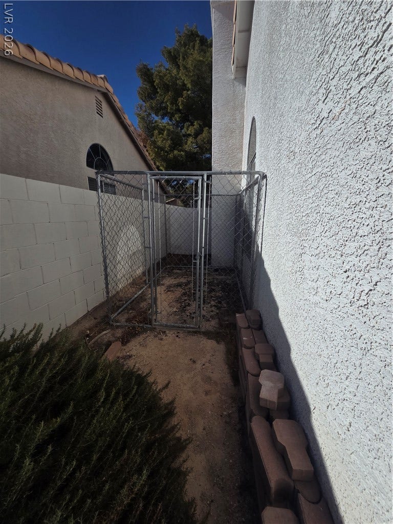 1429 Hawkwood Road, Henderson, NV 89014 A functional side yard features concrete block walls, stucco finishes, and a chain-link kennel enclosure.