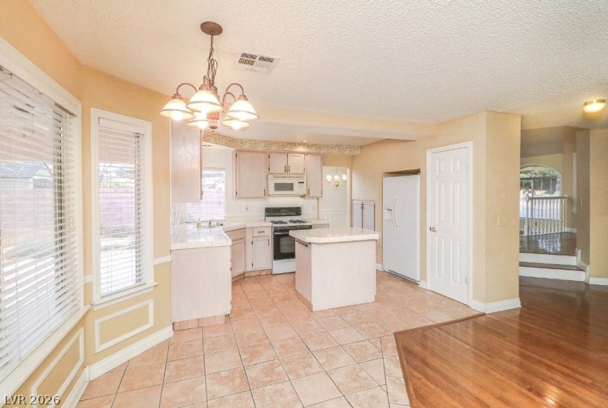 1429 Hawkwood Road, Henderson, NV 89014 Tiled flooring and wood transitions define this functional kitchen layout with dual dining areas.
