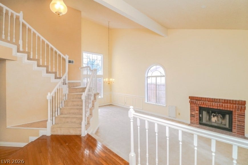 1429 Hawkwood Road, Henderson, NV 89014 A brick fireplace anchors the light-filled main level featuring soaring vaulted ceilings and polished wood floors.
