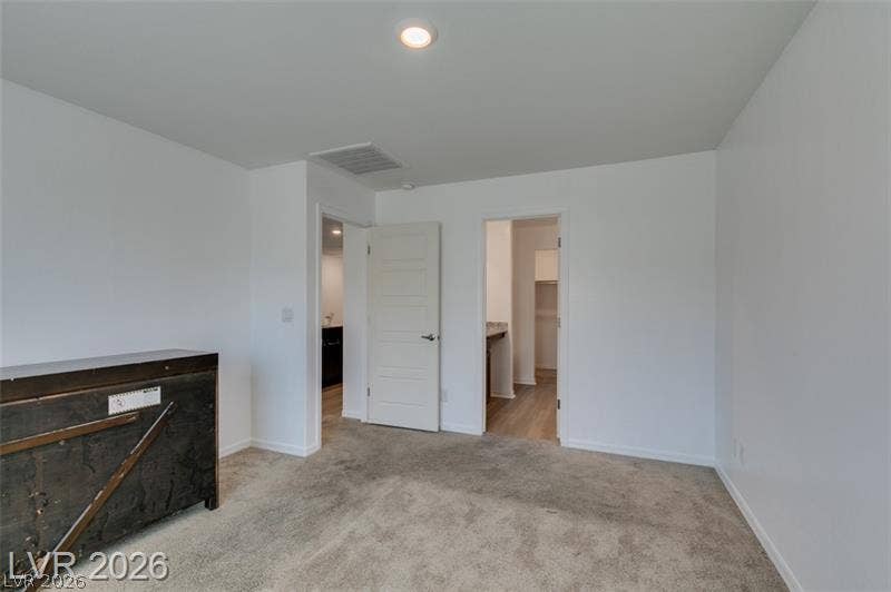 A spacious bedroom offers wall-to-wall carpeting and neutral-toned finishes.