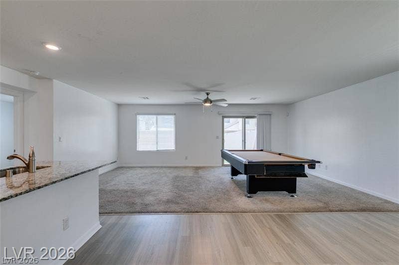 An open floorplan design seamlessly connects the laminate-floored foreground to the carpeted recreation space.