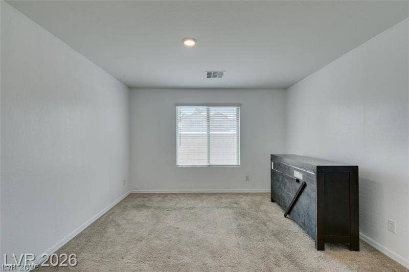 Plush carpeting anchors this versatile room with a single recessed light overhead.