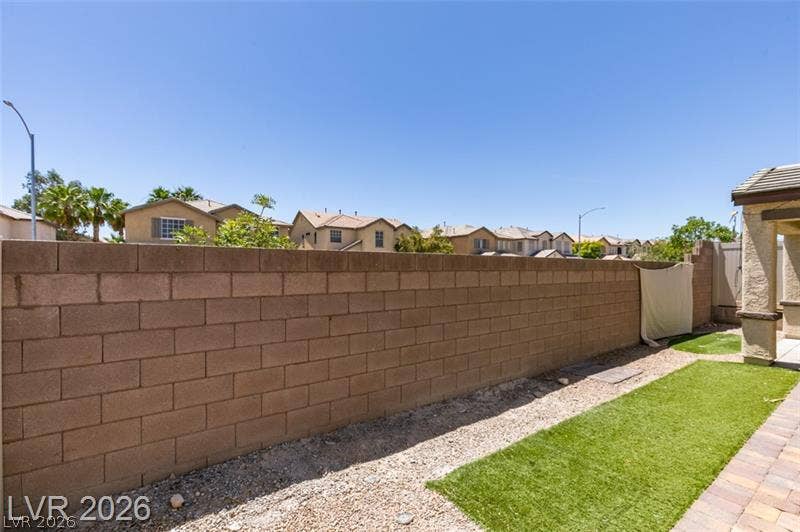 A sturdy block privacy fence encloses the low-maintenance yard under clear desert skies.