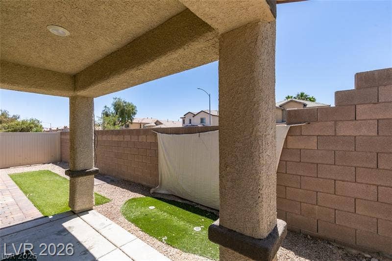 Shaded concrete patio columns overlook a private fenced yard with low maintenance turf.