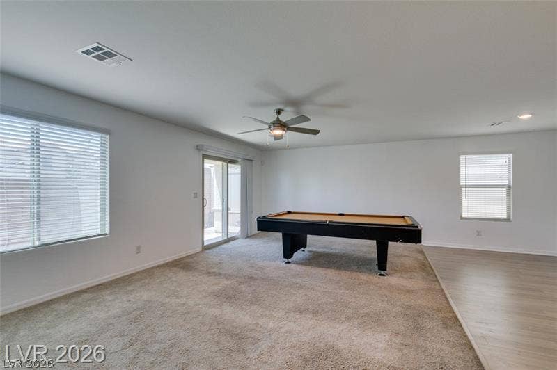 An open recreation space features carpeted flooring and sliding glass door access.