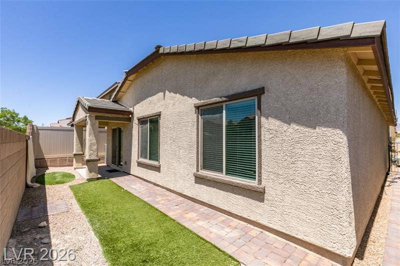 Textured stucco exterior and paved pathways frame the back of this modern home.