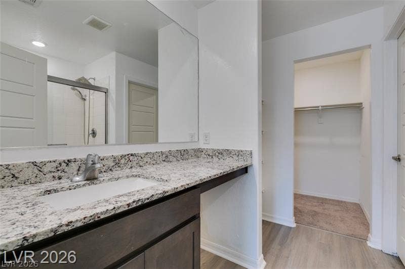 Polished granite counters and wood-look flooring lead directly into a spacious walk-in closet.