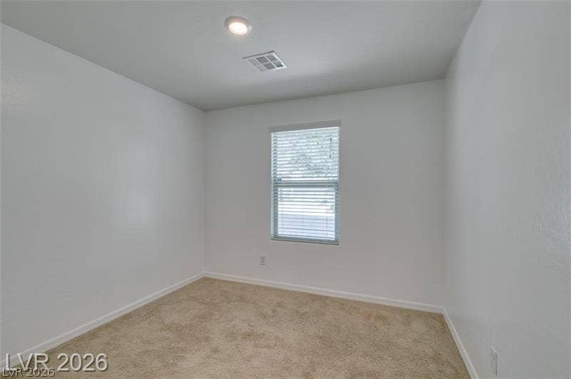 Soft carpeting pairs with neutral walls and recessed lighting in this versatile secondary bedroom.