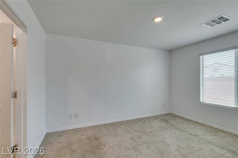 Plush carpeting underfoot complements the pristine walls and natural window light.