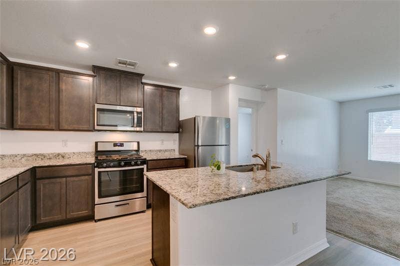 Rich wood cabinetry and sleek stone countertops define this modern, open-concept kitchen space.