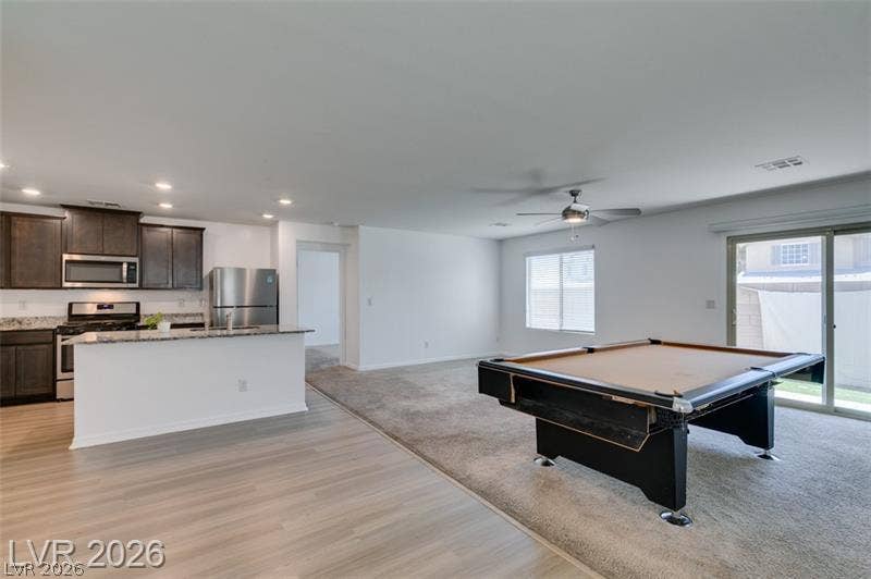 An open layout connects the kitchen to a versatile living space finished with carpet flooring.