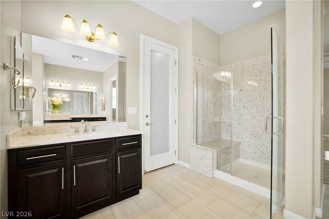 7230 Fresh Harvest Avenue, Las Vegas, NV 89131 Elegant primary bathroom complemented by a spacious glass-enclosed shower with added bench.
