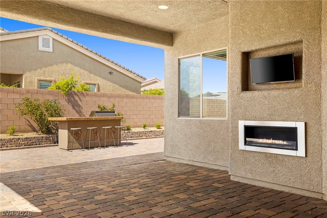 7230 Fresh Harvest Avenue, Las Vegas, NV 89131 An inviting outdoor living space features a built-in fireplace connected the house gas line rather than having a propane tank, a sized paver patio.