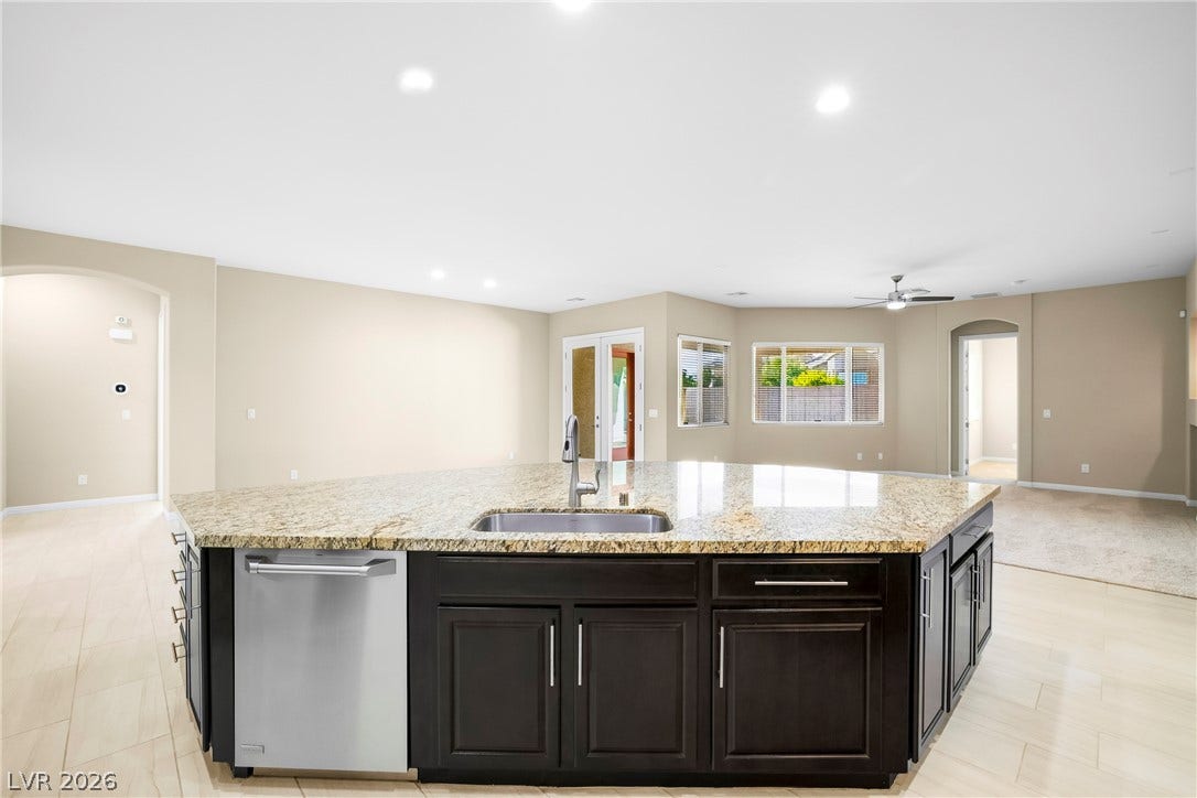 7230 Fresh Harvest Avenue, Las Vegas, NV 89131 A well-appointed kitchen island with gleaming granite countertops anchors this open-concept living space.