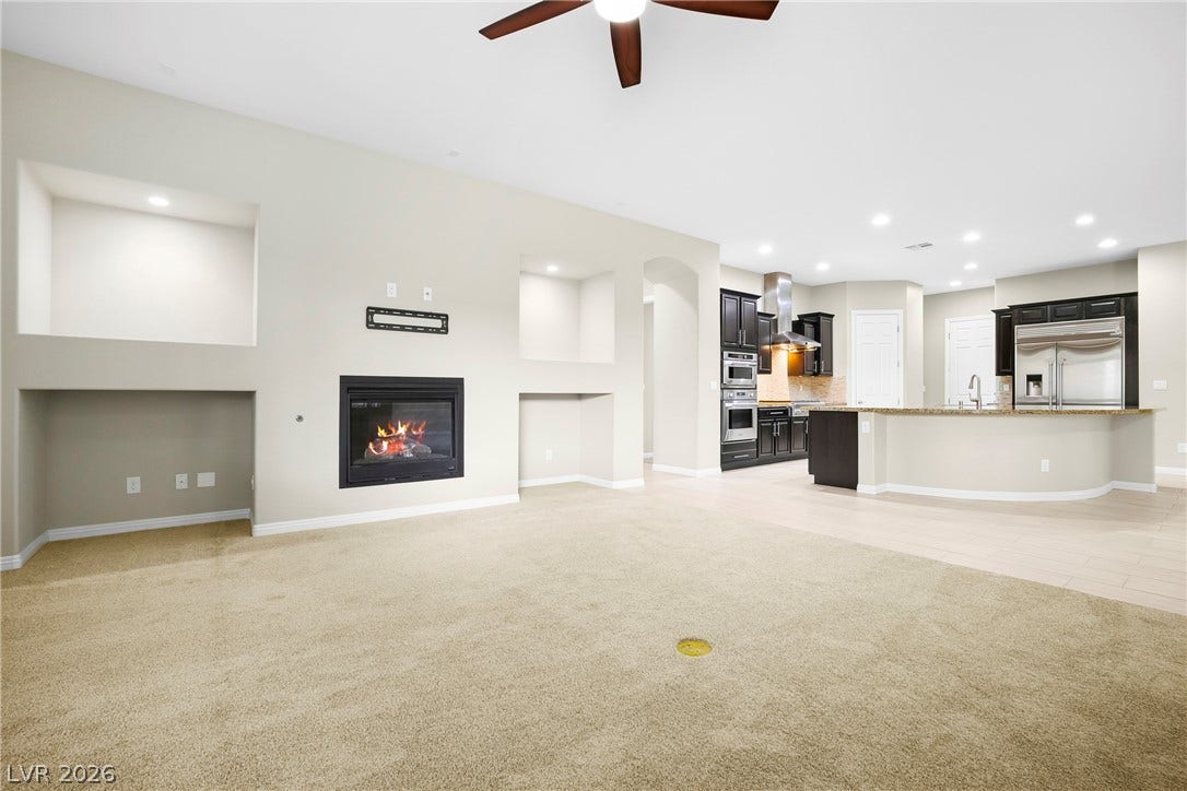 7230 Fresh Harvest Avenue, Las Vegas, NV 89131 A welcoming open-concept living space features a cozy fireplace and a seamlessly integrated kitchen.