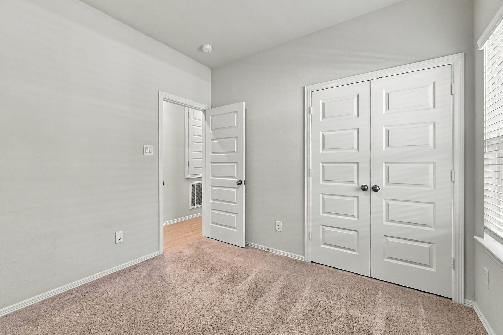 5702 Fresh View Court, Katy, TX 77493 Another view highlights the bedroom's practical layout, complete with a spacious closet concealed behind double paneled doors. The combination of high ceilings, plush carpeting, & generous wall space provides flexibility for arranging furniture while maintaining a comfortable, uncluttered feel.
