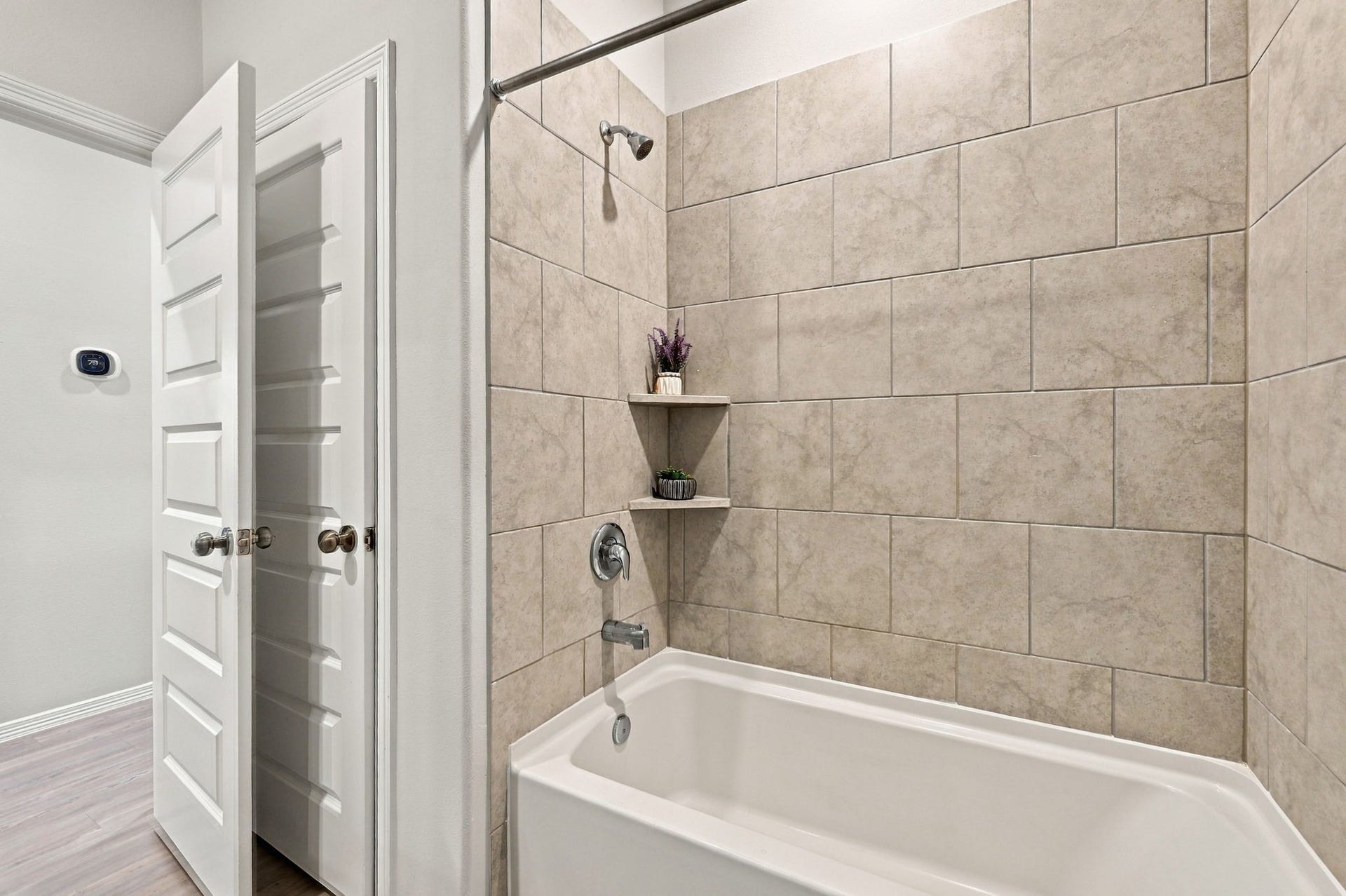 5702 Fresh View Court, Katy, TX 77493 The secondary bathroom features a spacious tub & shower combination surrounded by oversized neutral-toned tile, creating a timeless, polished appearance. Convenient built-in corner shelving offers additional space for bath essentials, while the classic finishes complement the home's cohesive interior design.