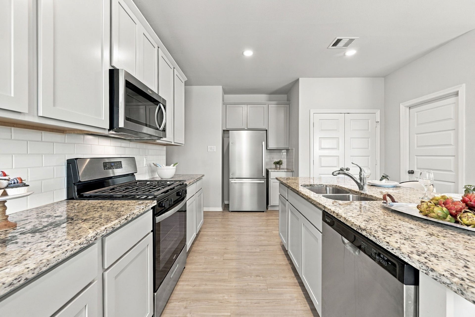 5702 Fresh View Court, Katy, TX 77493 A closer look reveals the kitchen's beautiful combination of granite surfaces, crisp white cabinetry, & timeless subway tile backsplash. Stainless steel appliances, including a gas range, built-in microwave, & refrigerator, complement the polished finishes, while the generous island features a double-basin sink & dishwasher.