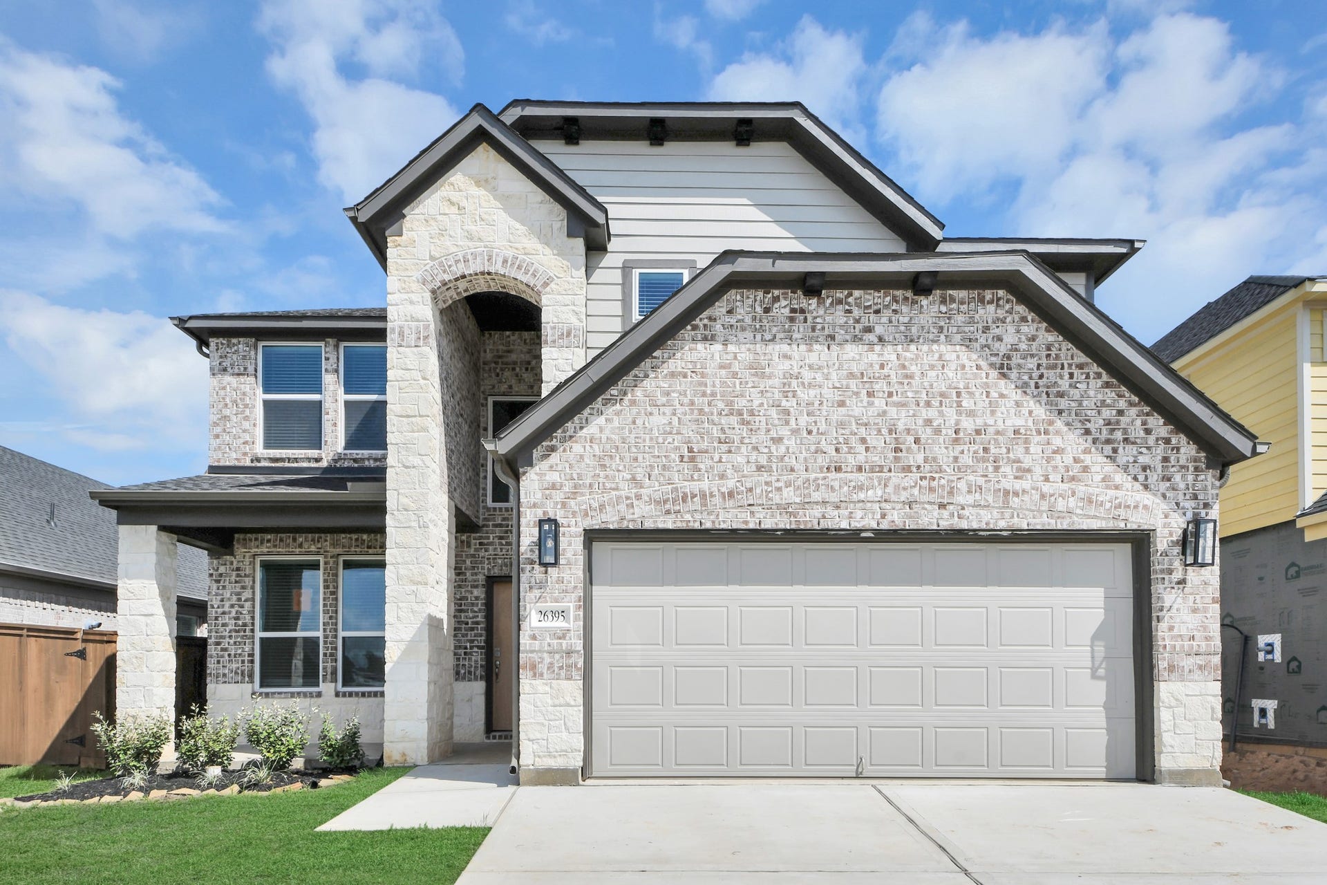 26395 Viva Drive, Magnolia, TX 77355 Meticulously maintained yard and lush landscape, paired with a premium elevation featuring captivating brick accents. Modern coach lights add a touch of contemporary elegance to the exterior.