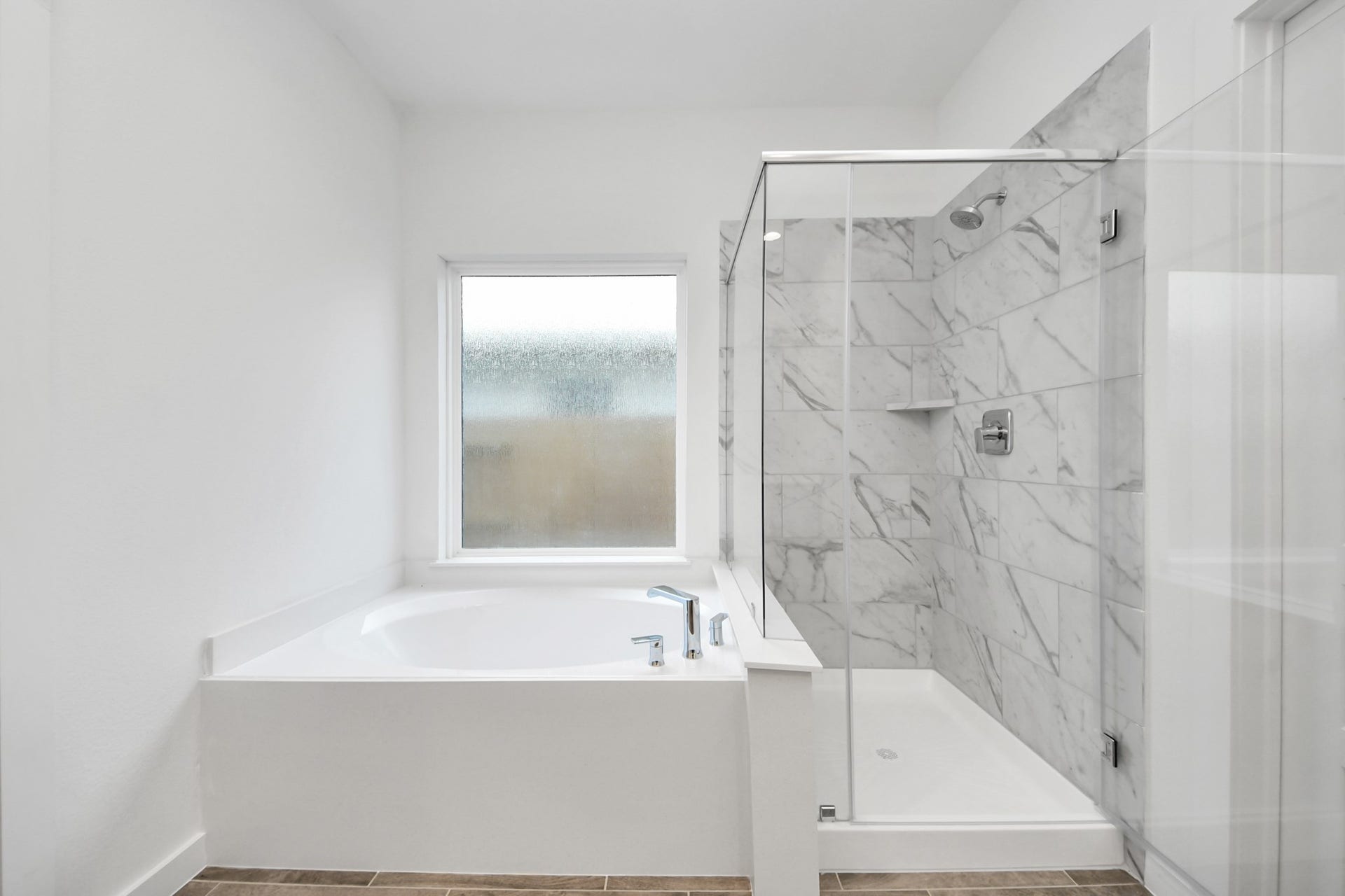26395 Viva Drive, Magnolia, TX 77355 Escape to a spa-like oasis in this primary bathroom. Enjoy a walk-in shower with tile surround, a separate garden tub with custom detailing, and an elegant vanity featuring light countertops, modern hardware, and beautiful vanity lights. Experience luxury and relaxation in every detail.