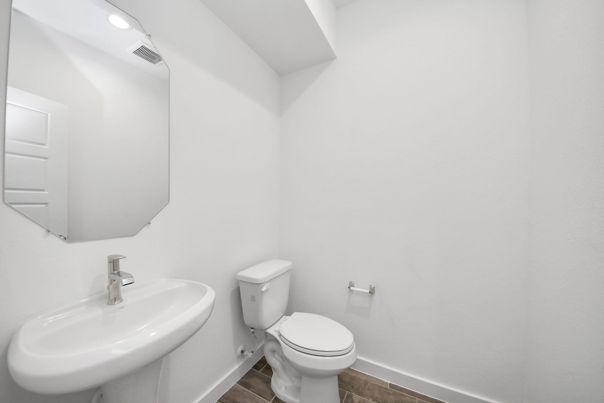 26395 Viva Drive, Magnolia, TX 77355 This half bathroom features a stylish pedestal sink, modern hardware, and bright recessed lighting, creating a sleek and inviting space.