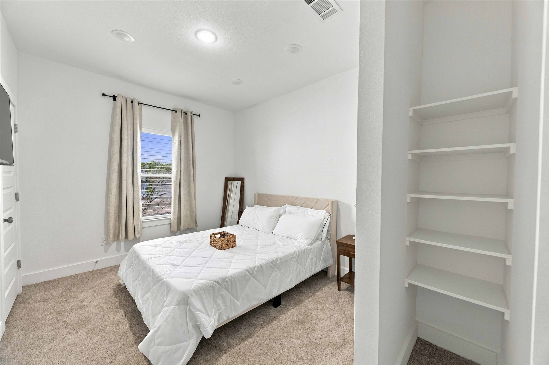 Bright, inviting second bedroom featuring recessed lighting, plush carpet, and convenient built-in shelving for added storage.