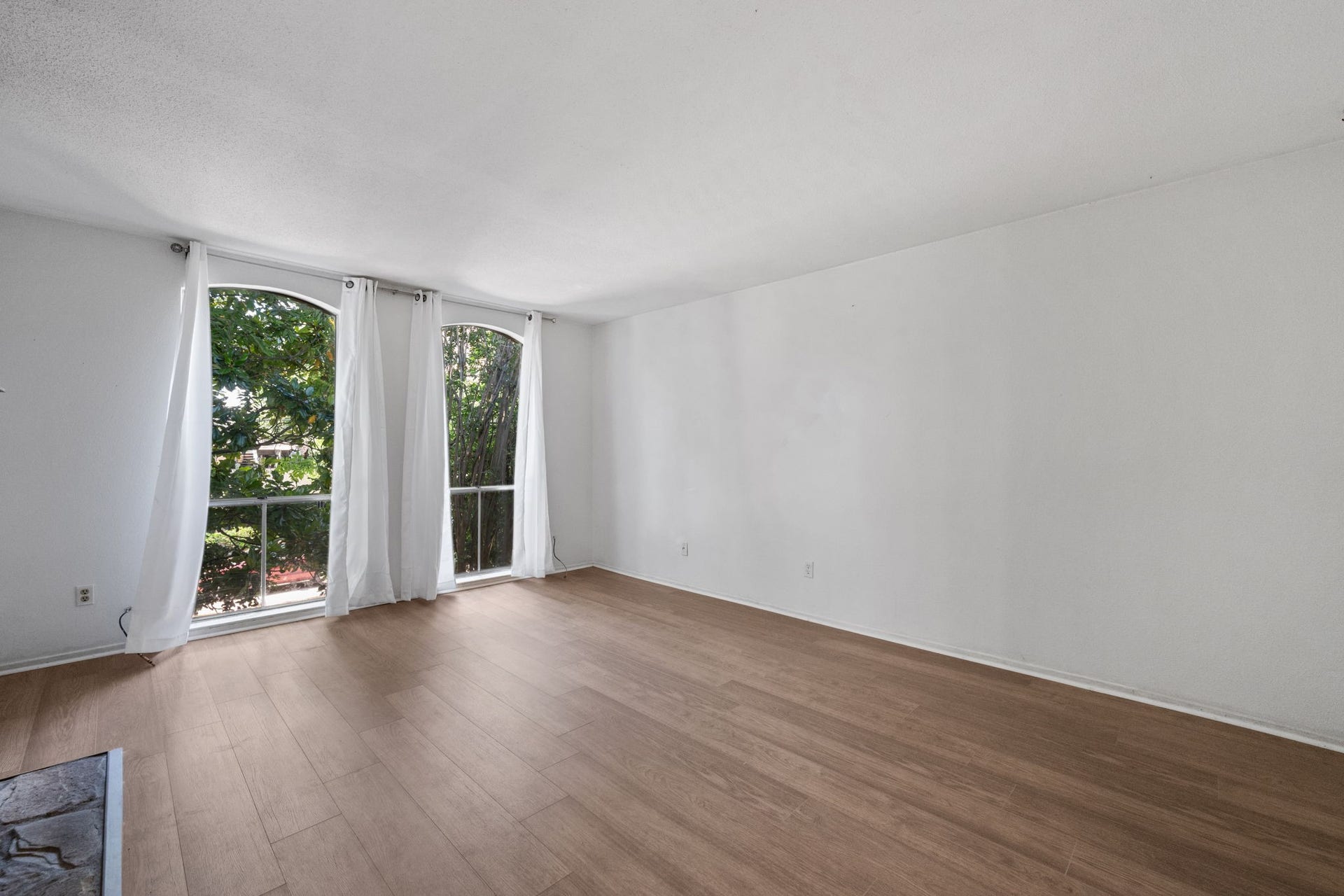 4649 Wild Indigo Street, #337, Houston, TX 77027 Spacious room with large arched windows, offering abundant natural light and views of lush greenery, complemented by elegant wood flooring.