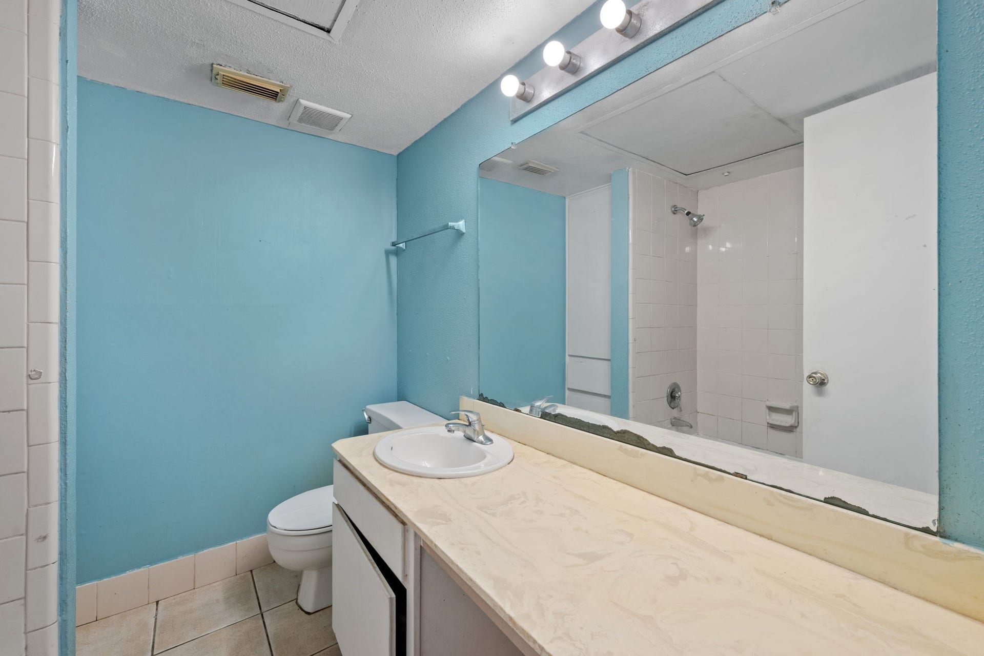 4649 Wild Indigo Street, #337, Houston, TX 77027 Bright bathroom with a spacious vanity, large mirror, and a shower-tub combination, all complemented by soothing blue walls.
