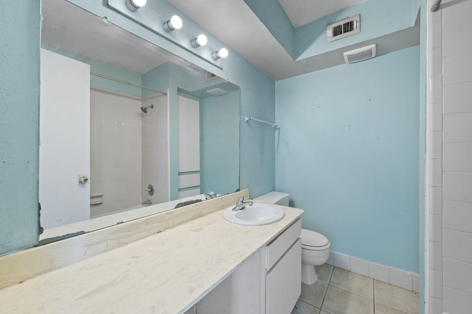 4649 Wild Indigo Street, #337, Houston, TX 77027 Bright bathroom with sky-blue walls, a spacious vanity, and a large mirror, offering a clean and functional space.