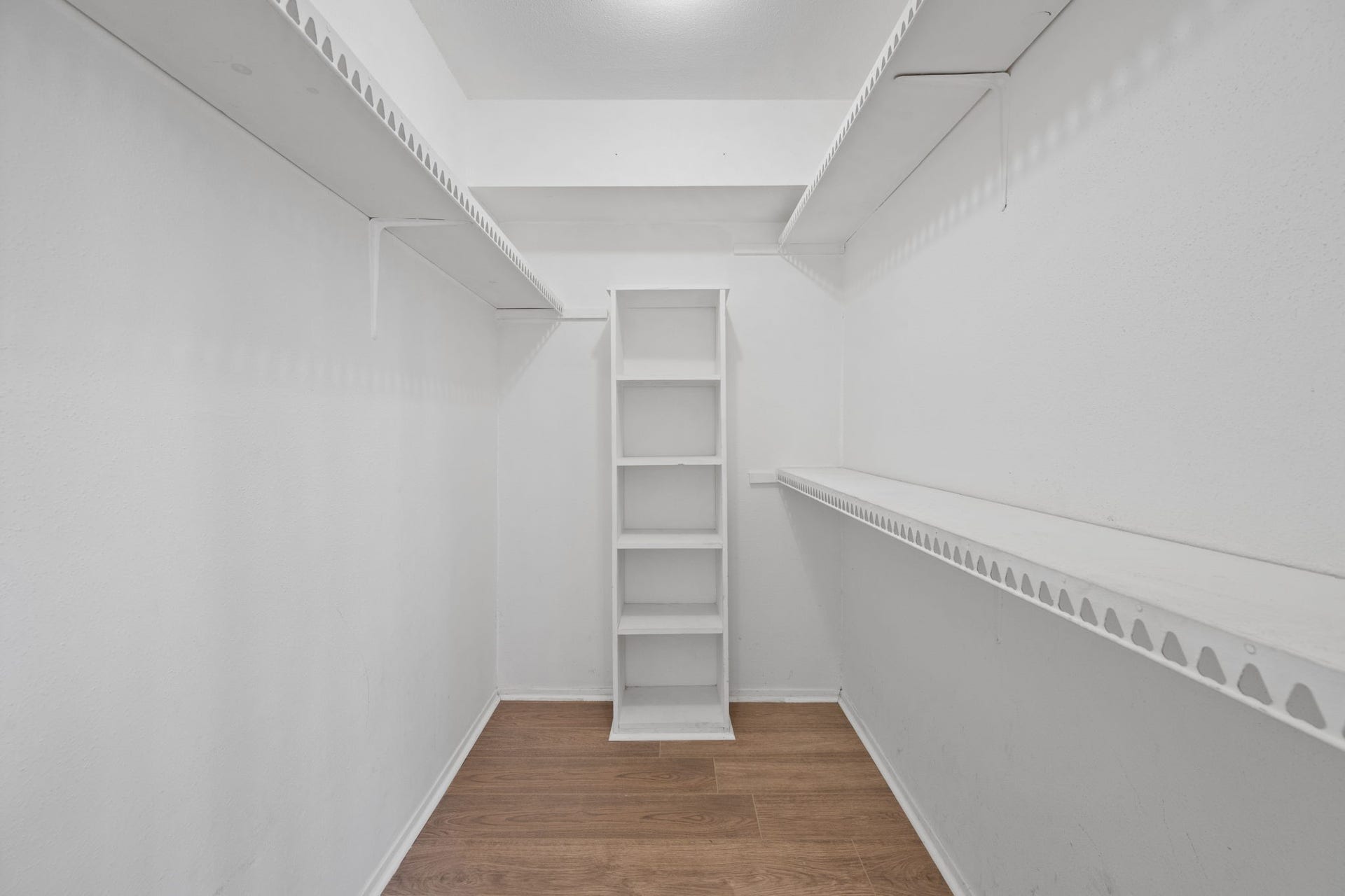 4649 Wild Indigo Street, #337, Houston, TX 77027 Spacious walk-in closet with ample shelving and storage, featuring elegant wood flooring and bright white walls.