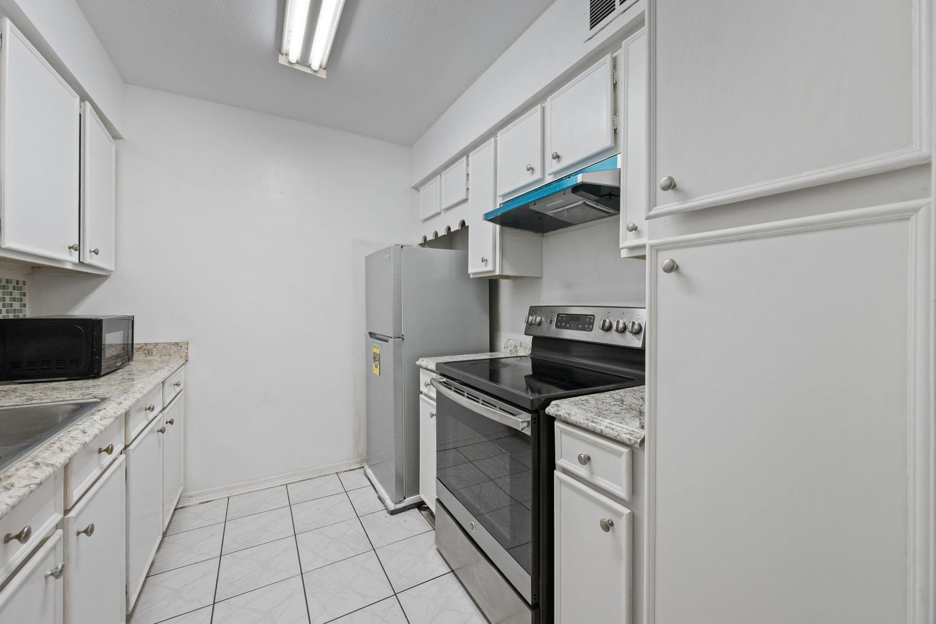 4649 Wild Indigo Street, #337, Houston, TX 77027 Bright, compact kitchen with modern appliances, white cabinetry, and sleek countertops providing a clean and functional cooking space.