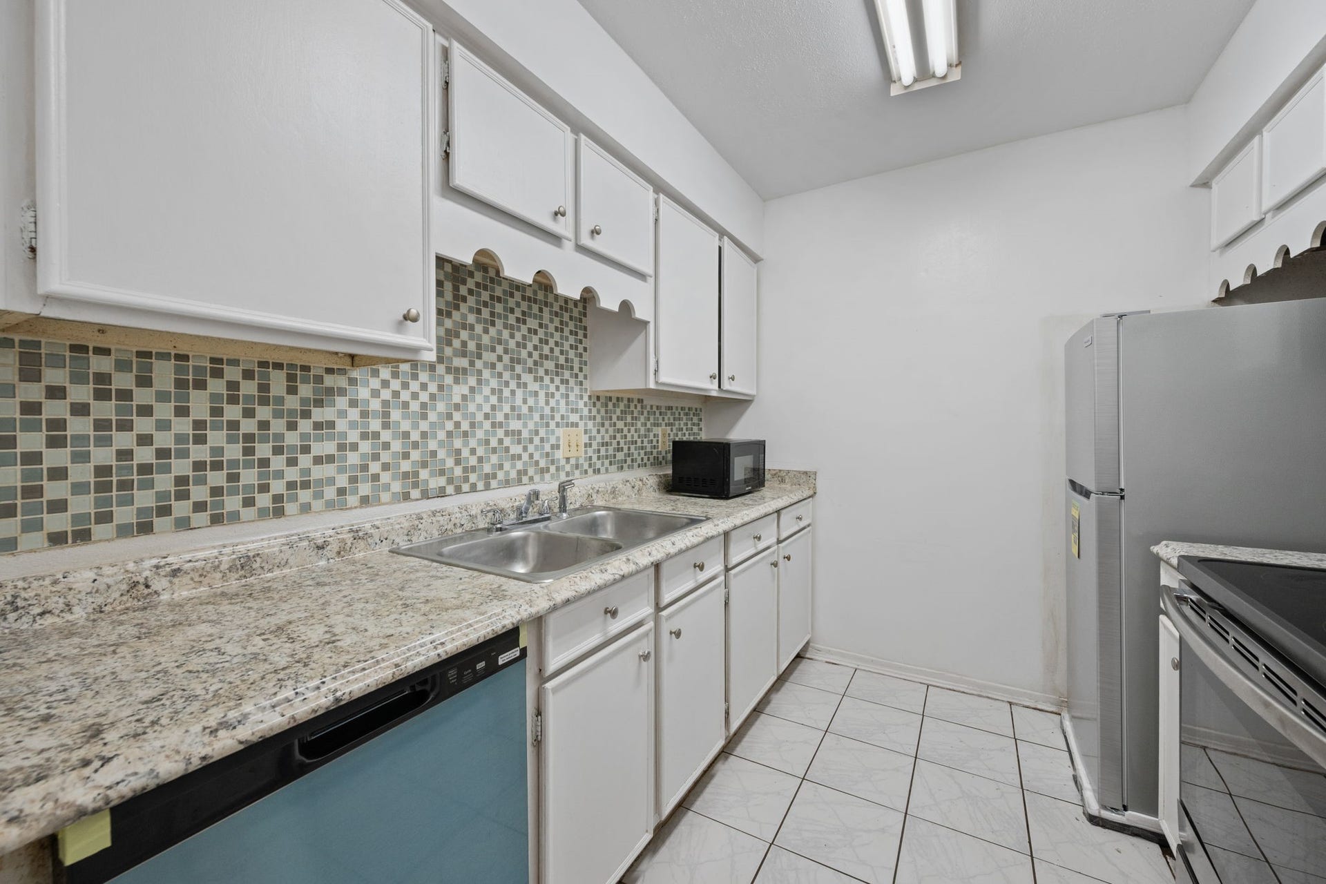4649 Wild Indigo Street, #337, Houston, TX 77027 Charming kitchen with sleek granite countertops, a stylish tile backsplash, and ample cabinetry for storage.