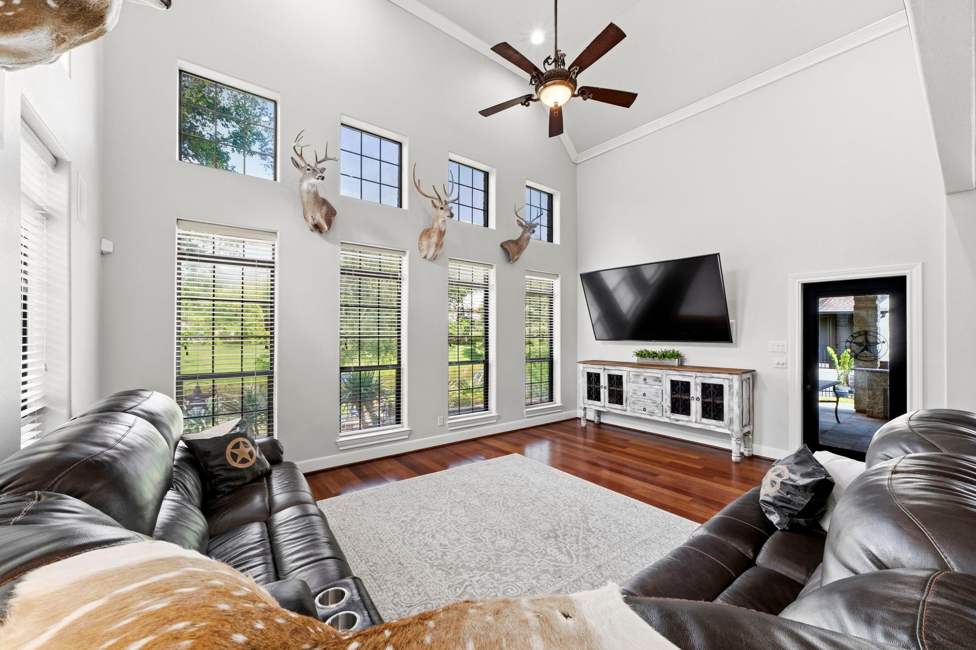 4903 Westerdale Drive, Fulshear, TX 77441 A soaring vaulted ceiling and expansive windows create an inviting family room where natural light and waterfront views take center stage. The door on the right leads to a covered patio area.
