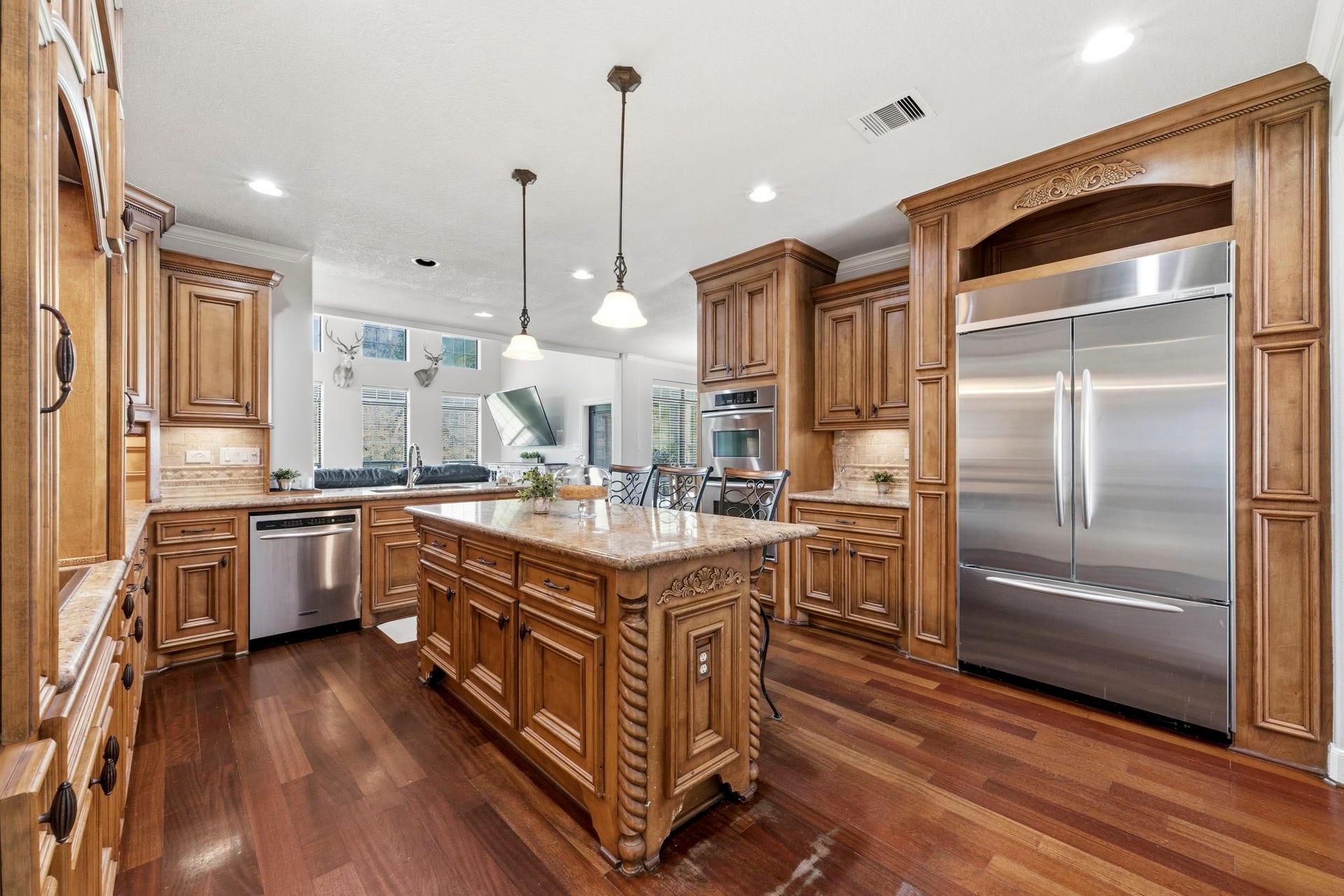 4903 Westerdale Drive, Fulshear, TX 77441 A built-in refrigerator blends seamlessly into the custom cabinetry, while the open-concept design keeps the kitchen connected to the spacious family room beyond.