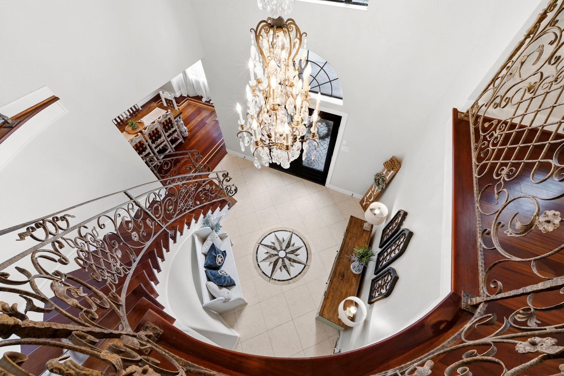 4903 Westerdale Drive, Fulshear, TX 77441 Transitioning upstairs, an elegant overlook showcases the dramatic two-story foyer, sweeping staircase, custom ironwork, and statement chandelier.