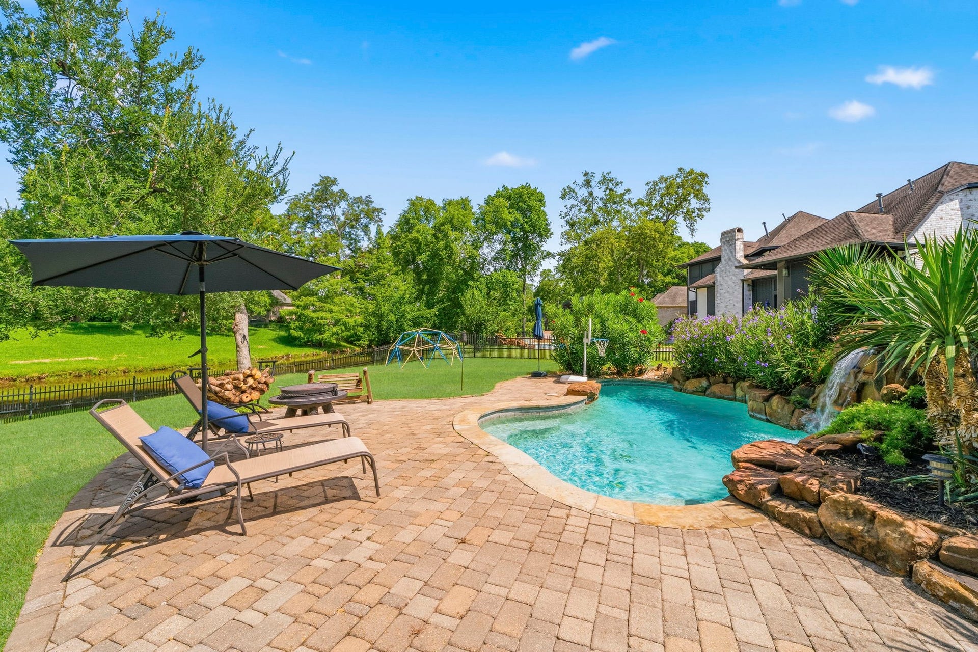 4903 Westerdale Drive, Fulshear, TX 77441 Resort-style backyard with sparkling pool, waterfall, expansive patio, and peaceful canal views.