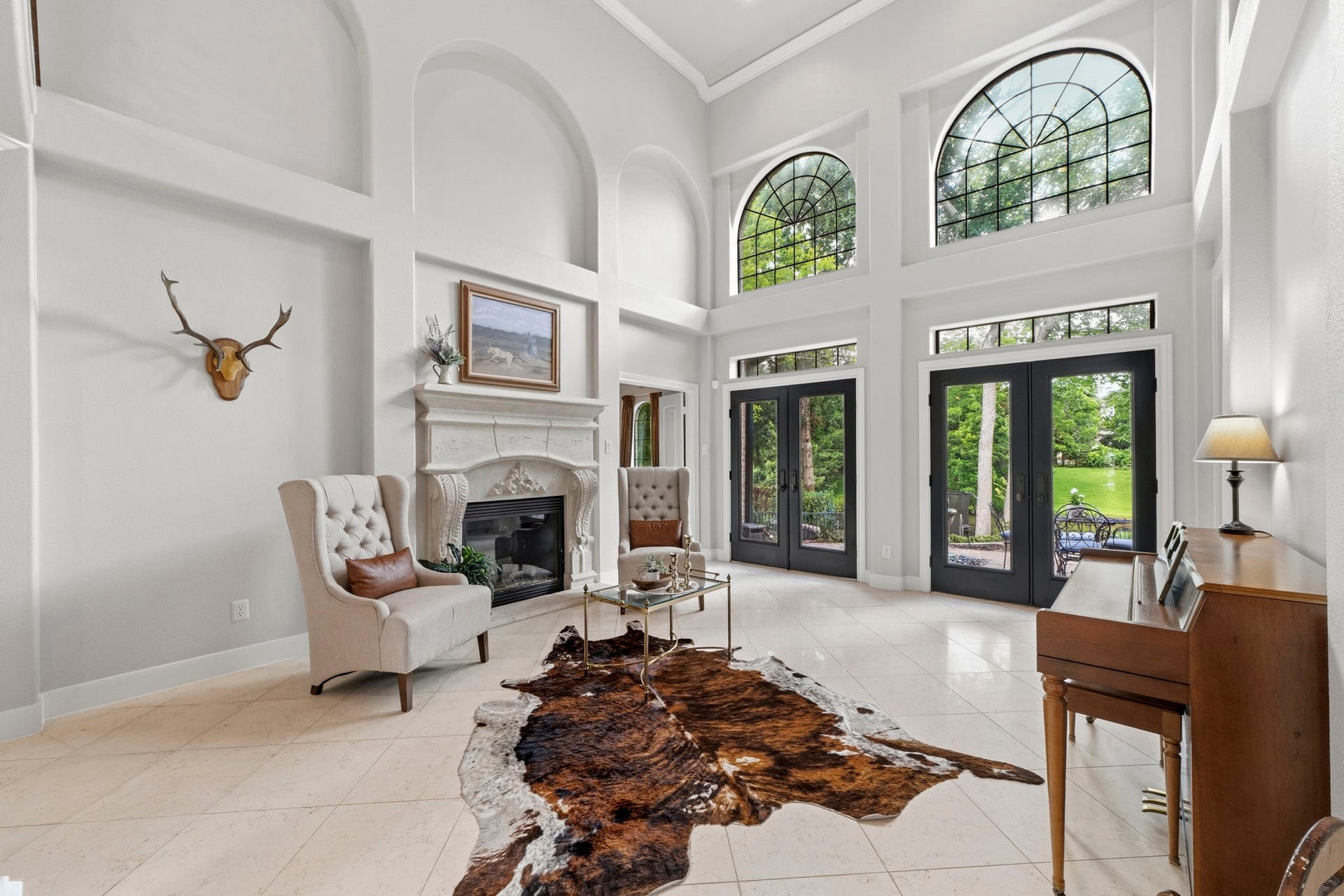 4903 Westerdale Drive, Fulshear, TX 77441 The formal living room impresses with soaring 18' ceilings, a dramatic wall of arched windows, an ornate stone fireplace, and double French doors that open to the backyard patios and tranquil water views.