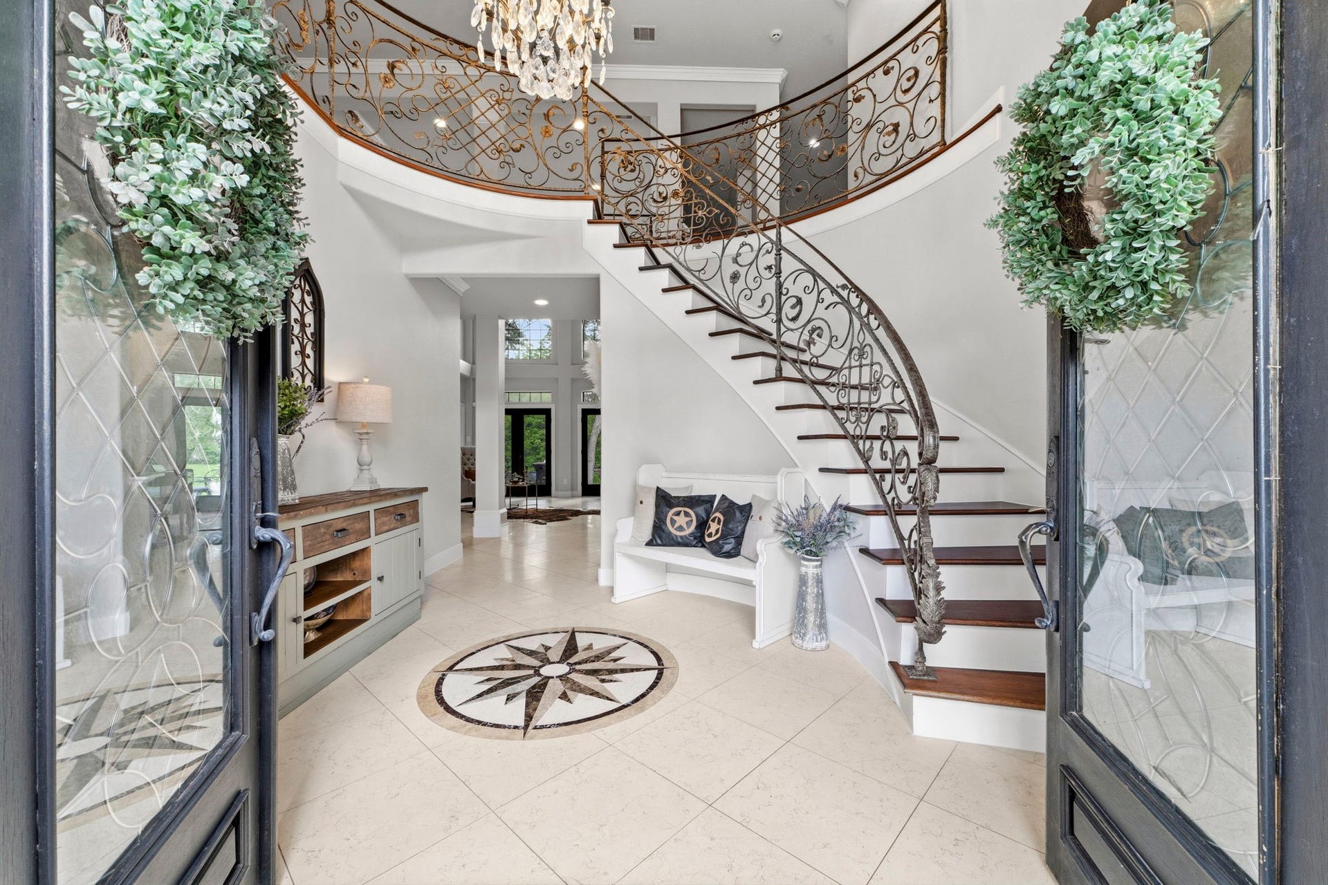 4903 Westerdale Drive, Fulshear, TX 77441 A dramatic two-story foyer welcomes guests with soaring 19' ceilings, marble tile flooring, a sweeping curved staircase, and intricate wrought-iron balusters.