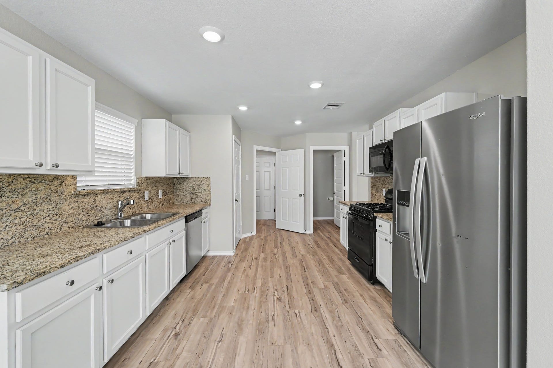 Spacious kitchen featuring white cabinetry, stainless steel appliances, gas range, recessed lighting, and ample counter space and storage.