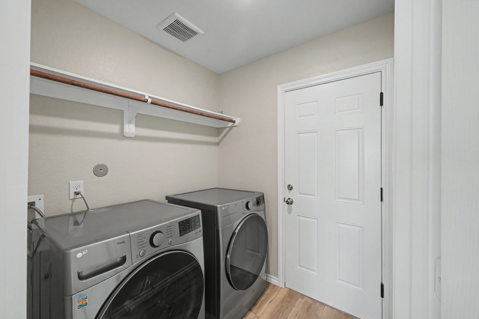 Convenient laundry room featuring washer and dryer, overhead shelving for additional storage, and direct access to the attached garage.