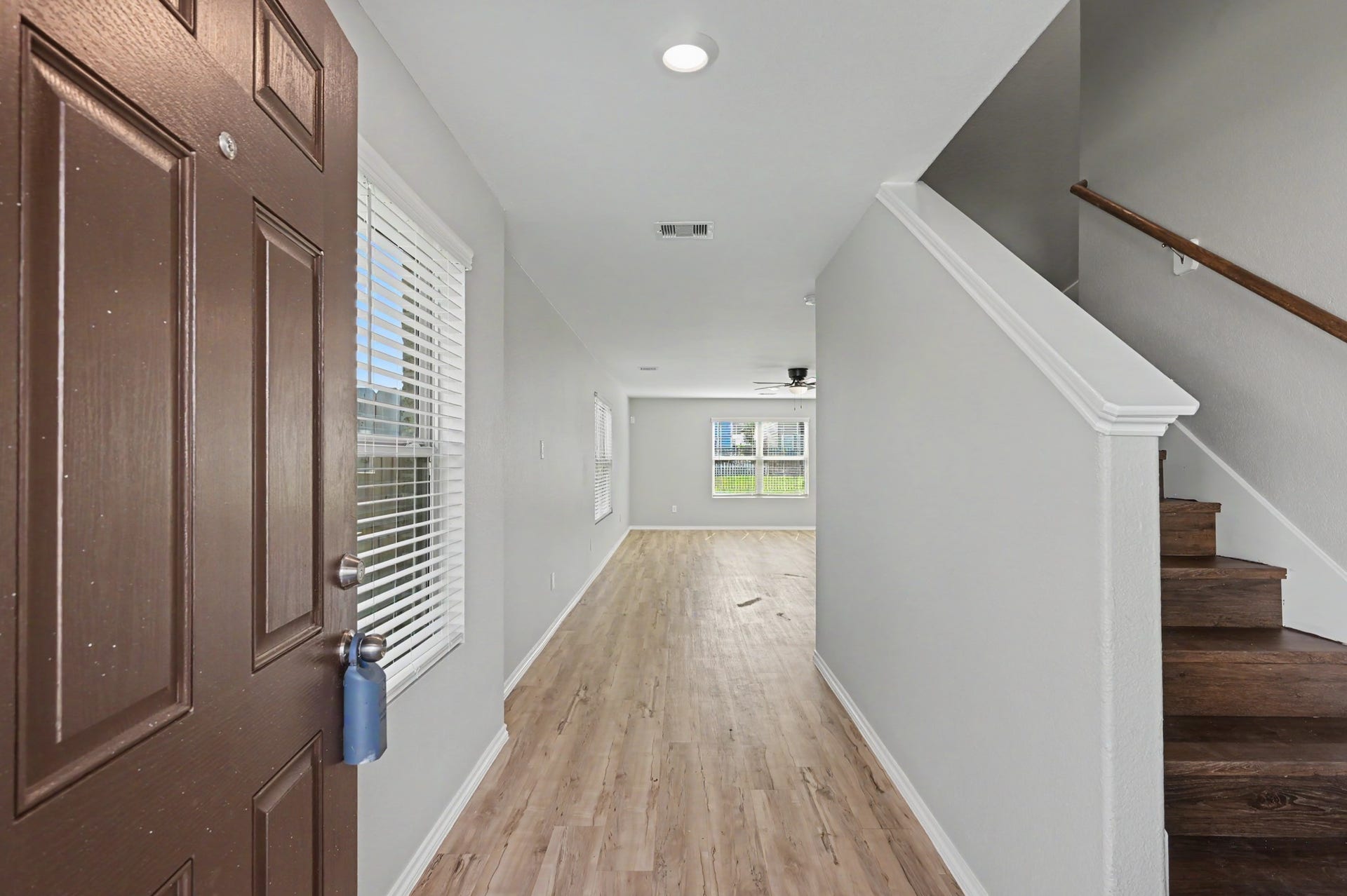 Welcoming entry foyer featuring wood-look flooring, neutral paint tones, abundant natural light, and a staircase leading to the second floor.