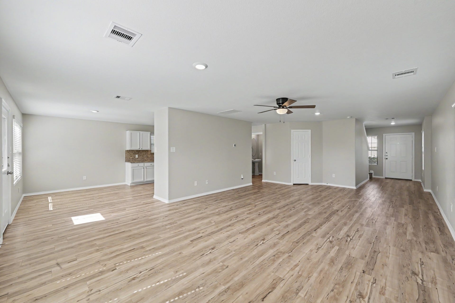 Another view of the spacious open-concept living and dining areas, featuring beautiful wood-look flooring, neutral finishes, recessed lighting, and abundant natural light. A versatile layout ideal for everyday living and entertaining.