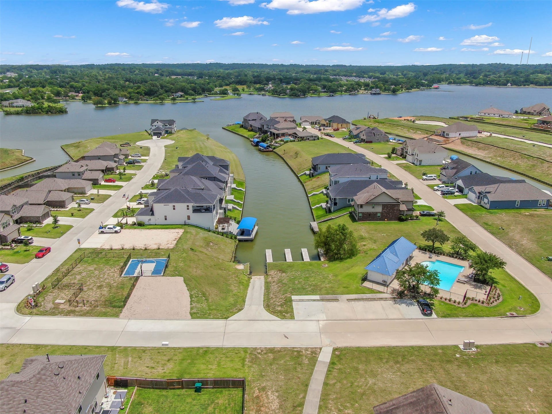 Aerial view of the community amenities featuring a swimming pool, boat ramp, and canal access to beautiful Lake Conroe.