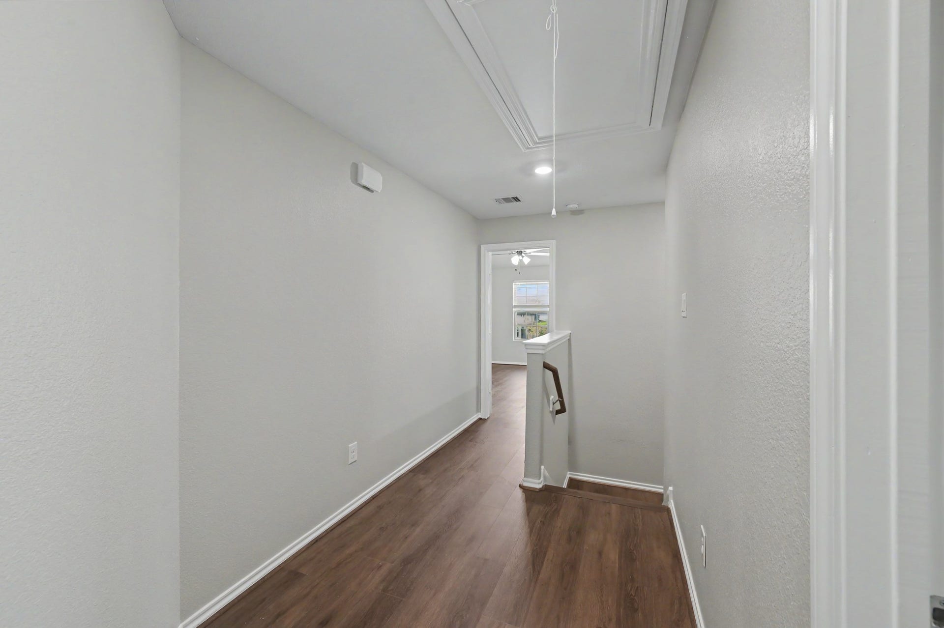 Upstairs hallway featuring wood-look flooring, neutral paint tones, recessed lighting, and convenient access to all bedrooms and two full baths.