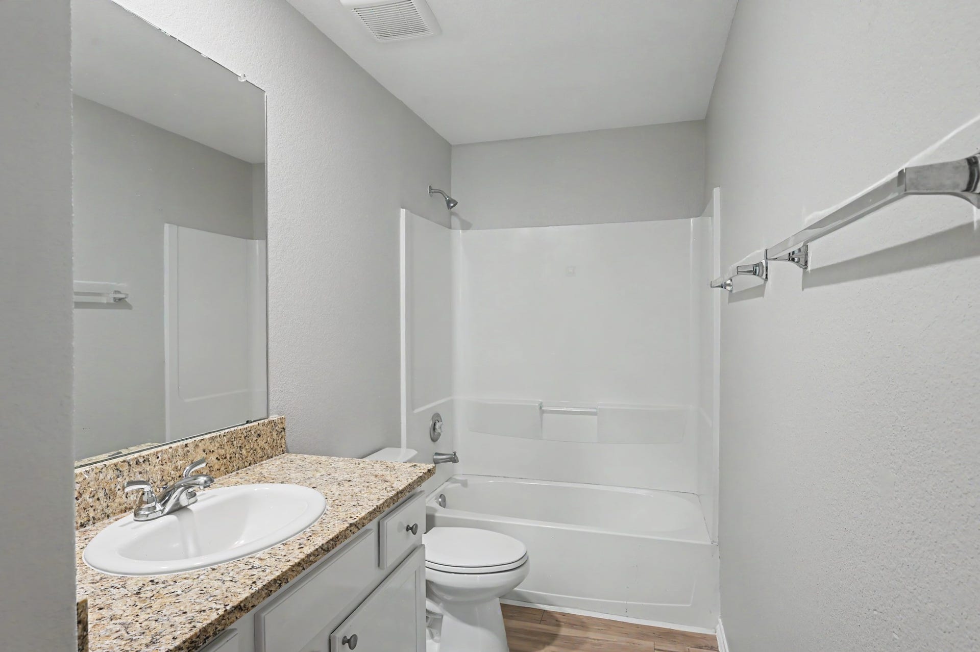 Upstairs secondary bath featuring granite countertop, white cabinetry, tub/shower combination, and wood-look flooring.