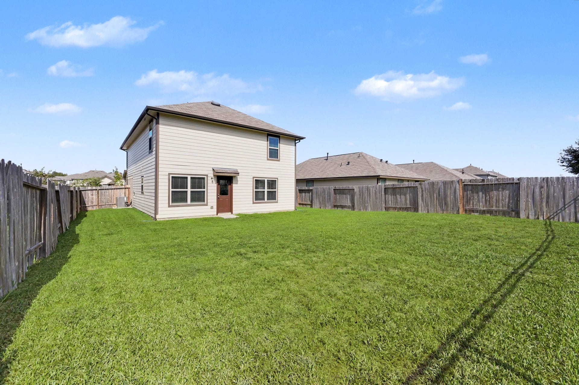 Rear exterior view showcasing the expansive, fully fenced backyard with plenty of green space for outdoor activities, entertaining, or creating your own outdoor retreat!