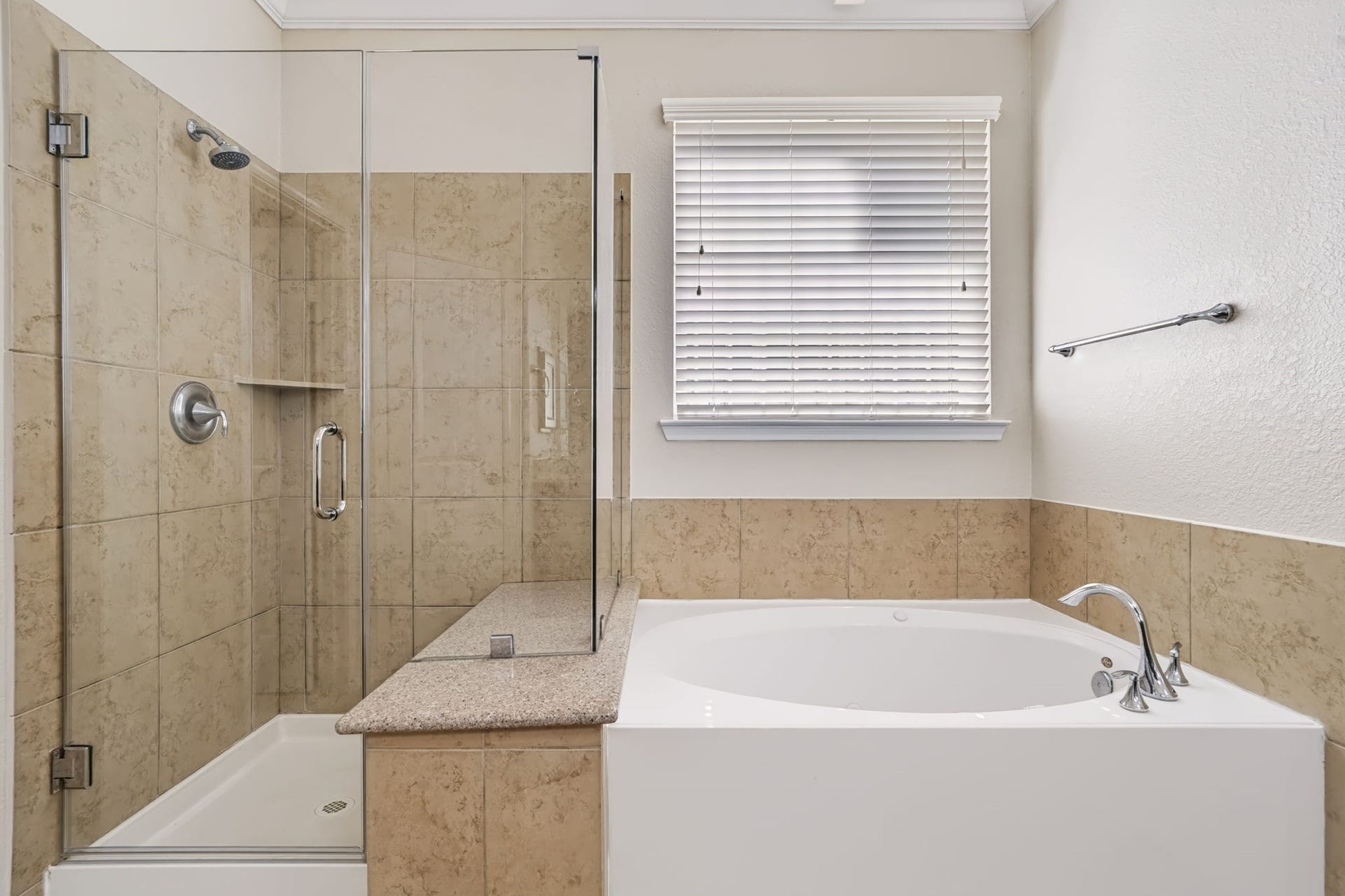 314 Trillium Drive, Sugar Land, TX 77479 A newly updated walk-in shower with a frameless glass enclosure and granite bench seat pairs beautifully with a round soaking tub, creating a spa-like retreat for relaxation.
