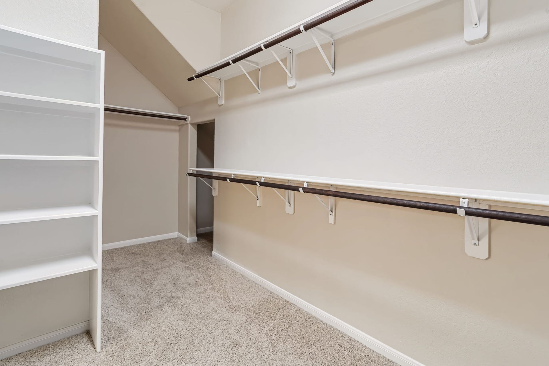314 Trillium Drive, Sugar Land, TX 77479 The spacious primary suite walk-in closet features built-in shelving, double hanging racks, and additional under-stair storage, providing ample room for clothing, accessories, and luggage.