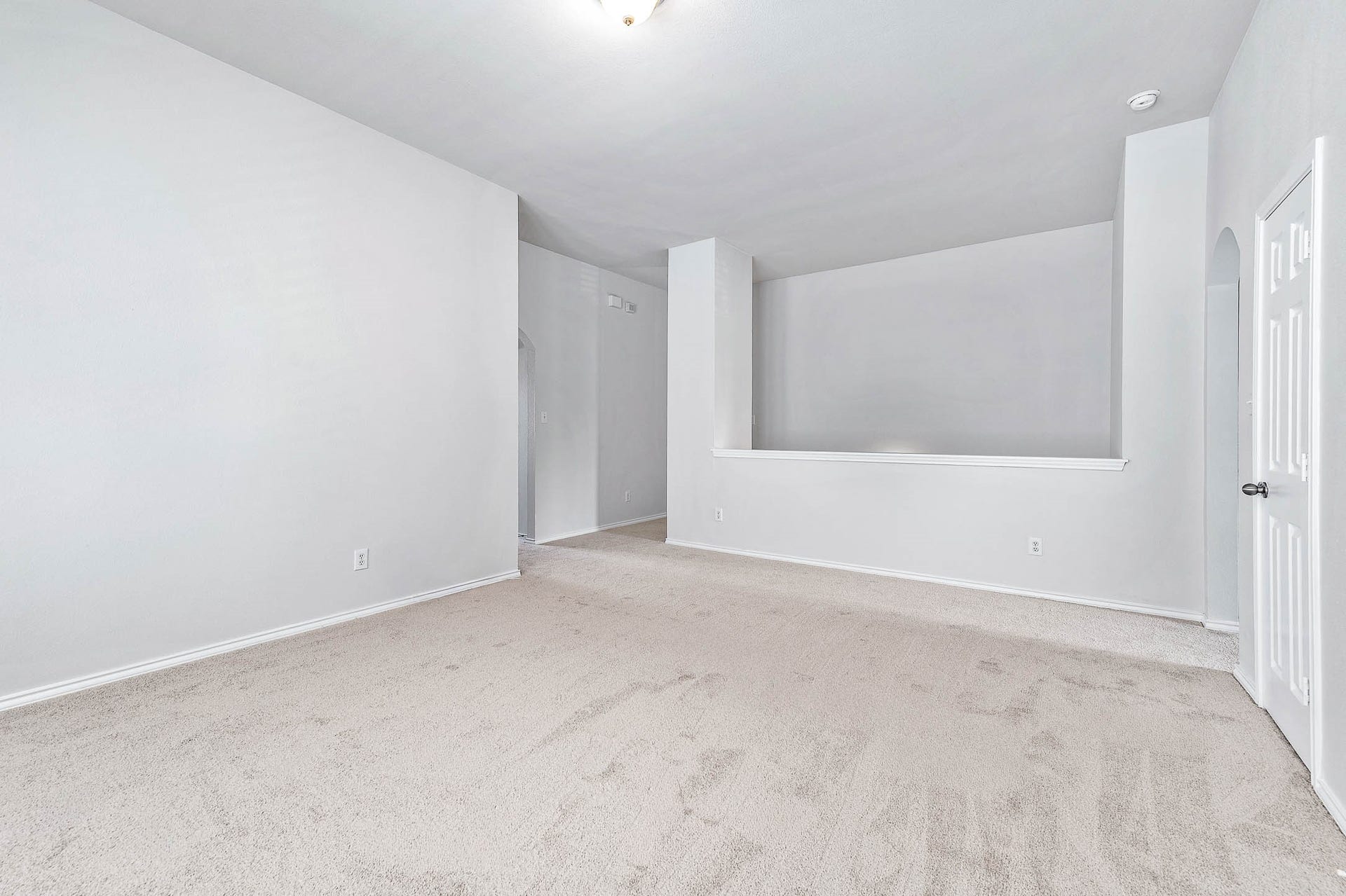 14923 ATMORE Place Dr, Houston, TX 77082 This spacious LOFT features neutral-toned carpet and walls, providing a blank canvas for customization. It includes a partial wall divider and an open doorway, offering potential for versatile use.