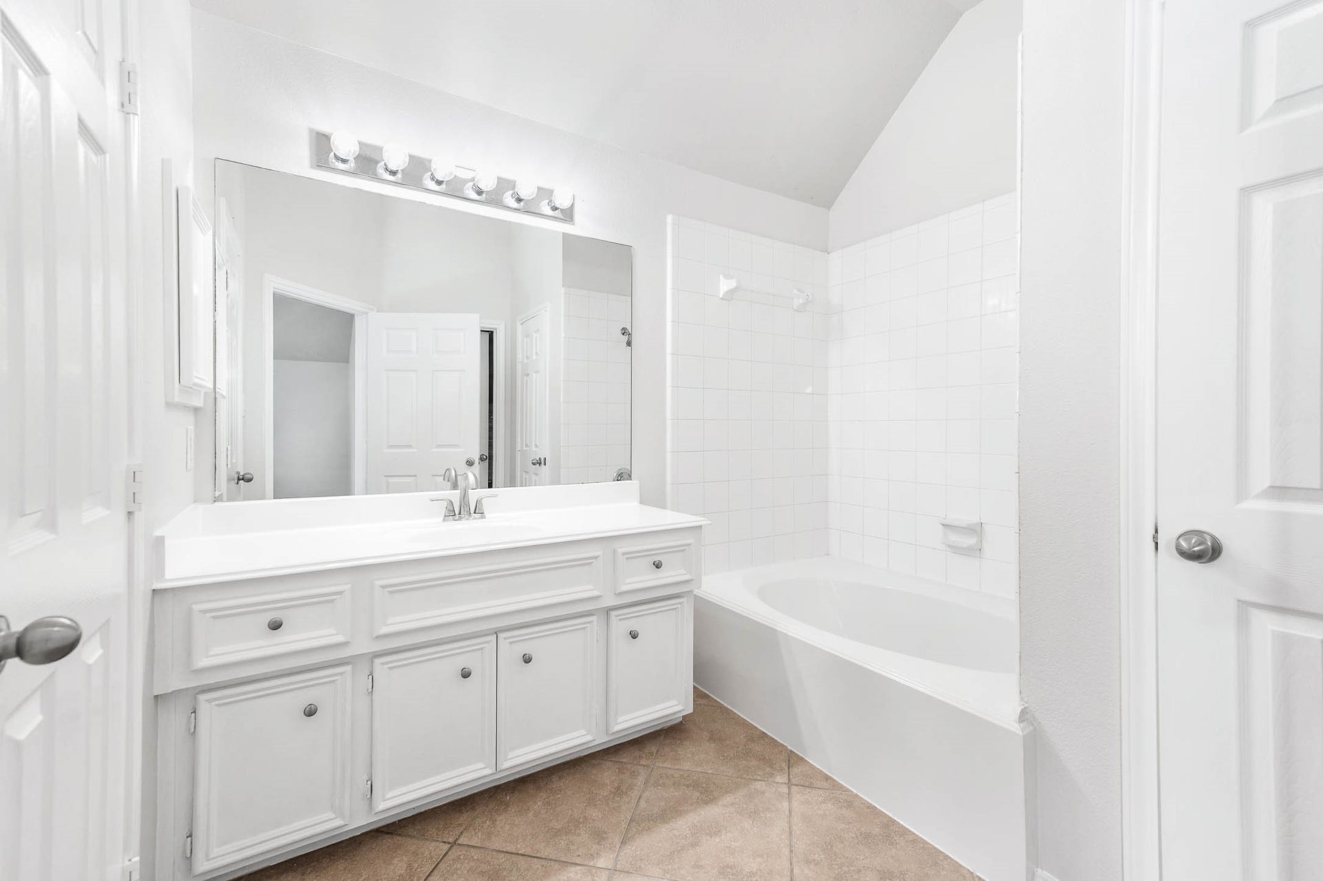 14923 ATMORE Place Dr, Houston, TX 77082 This bathroom features an OVERSIZE GARDEN Bathtub -ENJOY ! Clean design with a large vanity, ample storage, a spacious mirror with modern lighting, and a tiled shower-bathtub combo. The neutral tile floor complements the white cabinetry and walls.